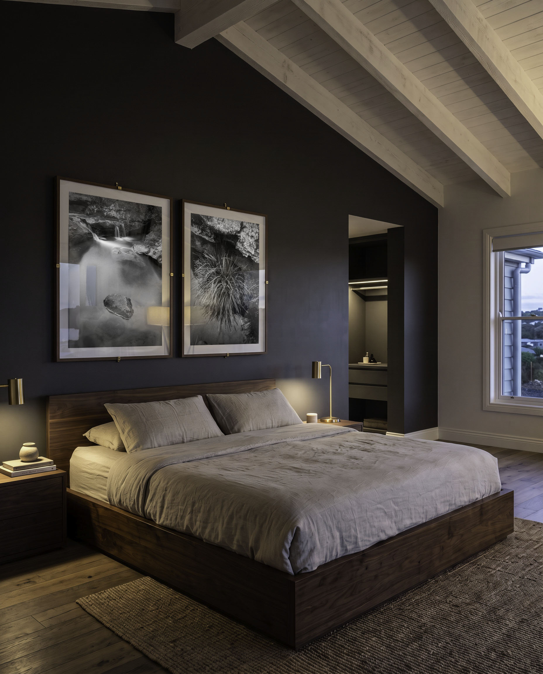 Dark, lamp-lit bedroom with two mounted prints above the headboard.