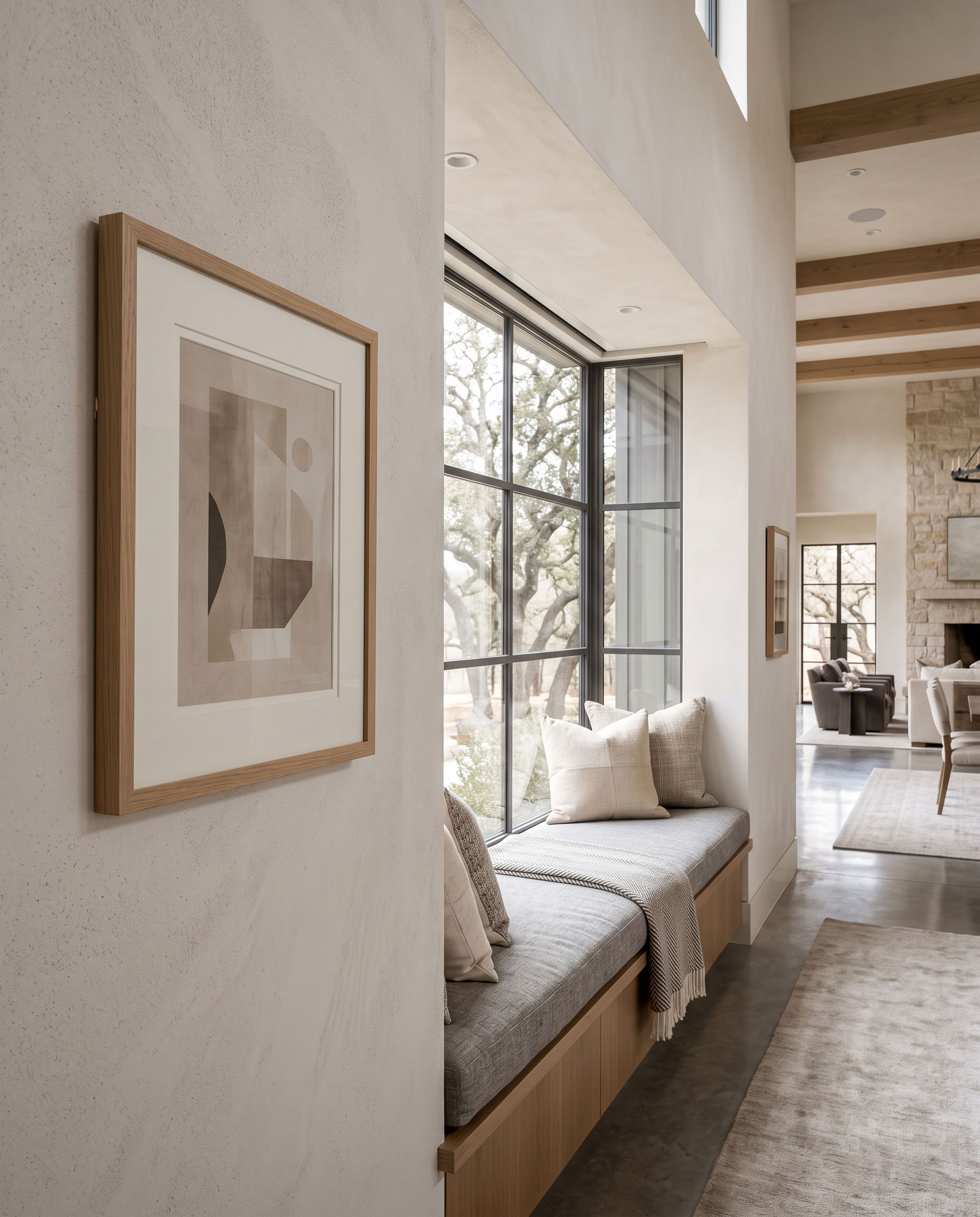 Window-seat reading nook with a framed vertical print on the adjoining wall.